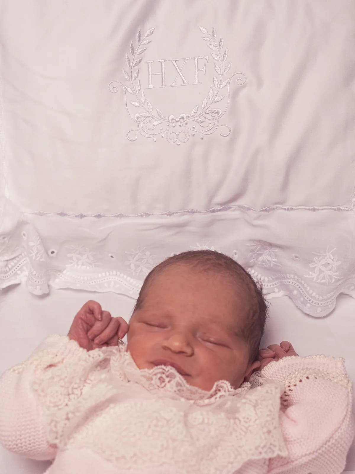 Baby Helena in delicate lace on a monogrammed pillow